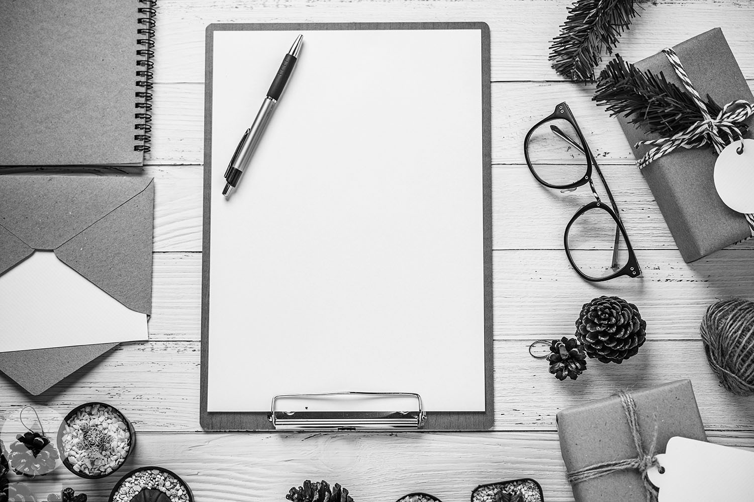 The clipboard is placed on a white wooden table with glasses, pe